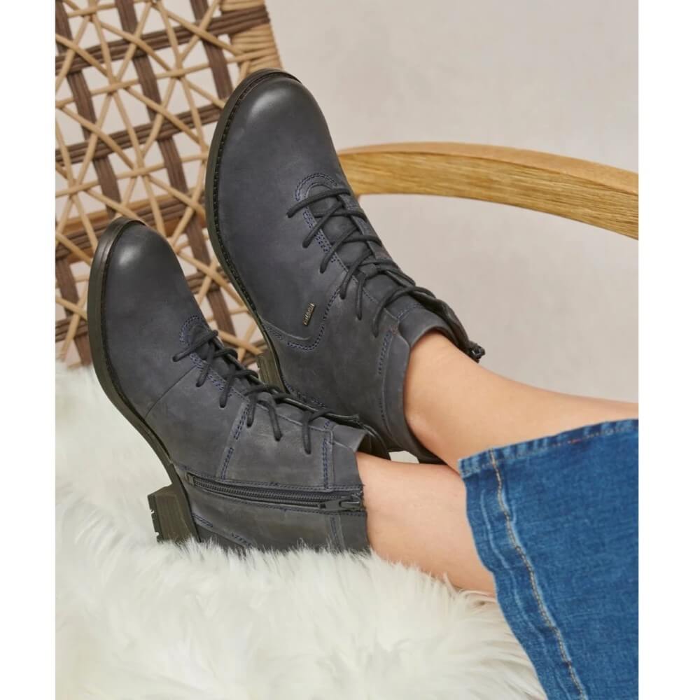 Person wearing a pair of Josef Seibel Kate 52 Waterproof Ocean Navy Leather Ankle Boots resting on a chair