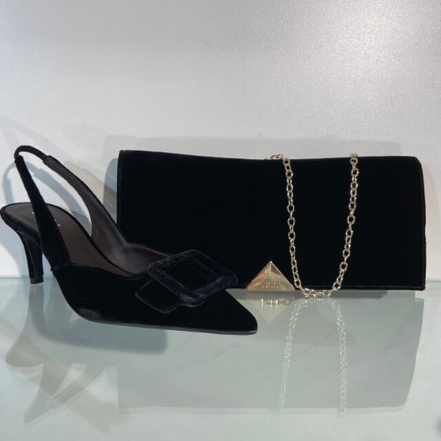 A Lodi Testa Brown velvet pointed-toe slingback high heel with a square buckle detail, displayed next to a matching Lodi brown velvet clutch bag with a gold chain strap and a gold-tone Gucci style logo plaque.