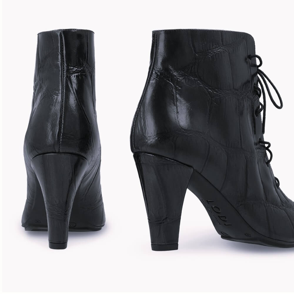 A pair Lodi Black ankle boots with a crocodile-embossed texture, featuring a block heel and black laces, shown from the back and side on a white background.