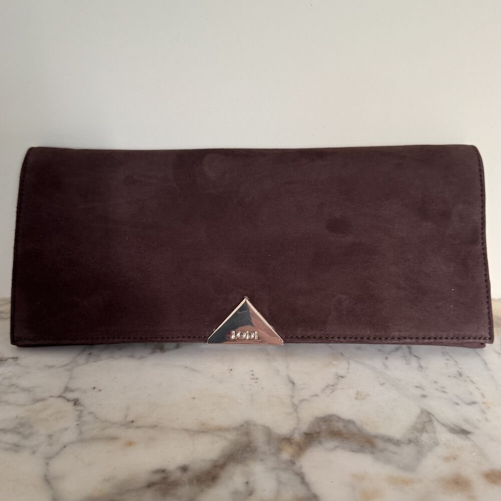 Brown suede leather clutch with a lodi brand logo on a marble surface