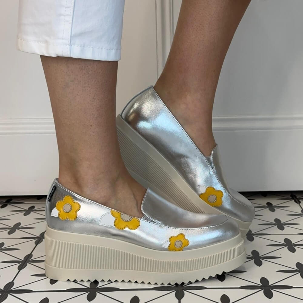 Marco Moreo Silver platform shoes with yellow flower designs worn indoors on a patterned floor.