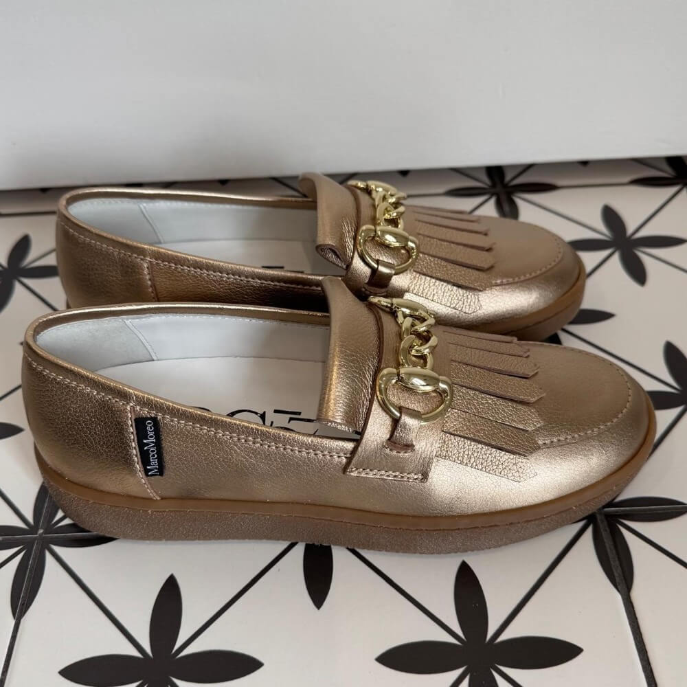 Pair of Marco Moreo gold bronze loafers with a gold buckle on a tiled floor. X760