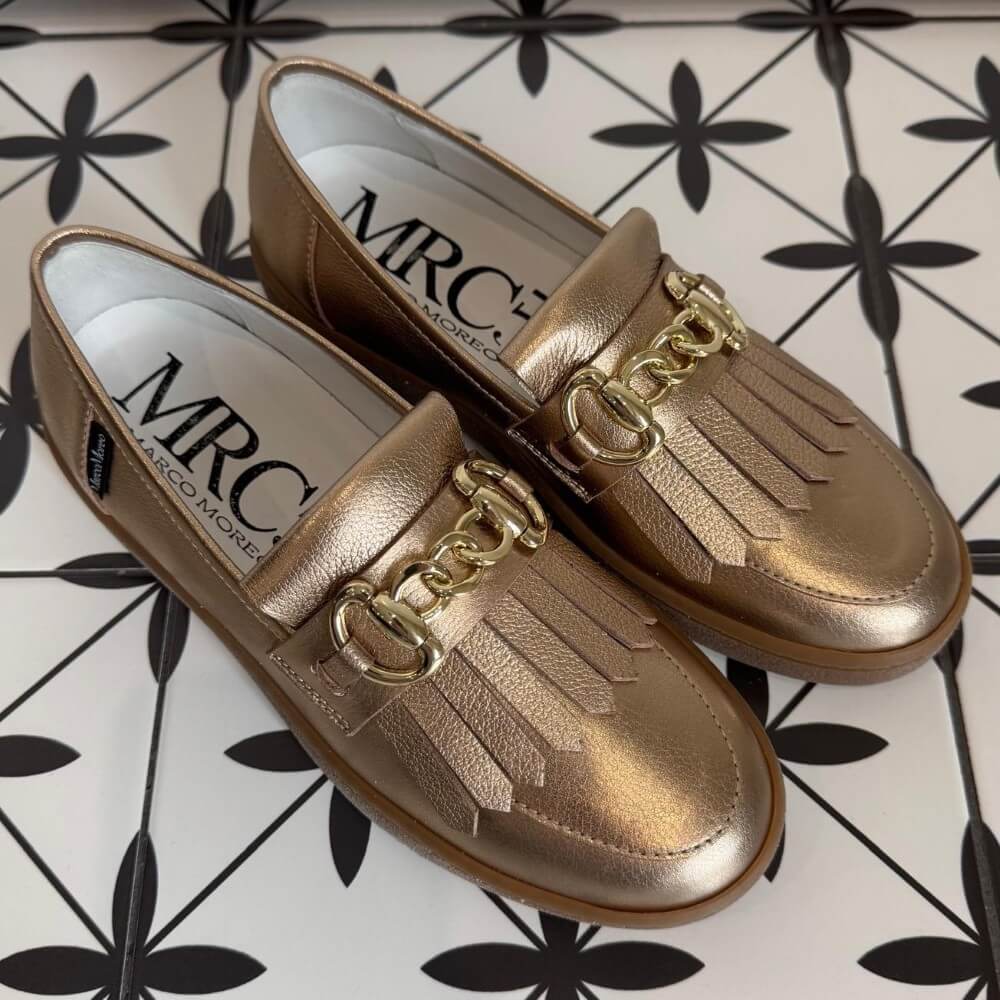Pair of Marco Moreo gold bronze loafers with a gold buckle on a tiled floor. X760