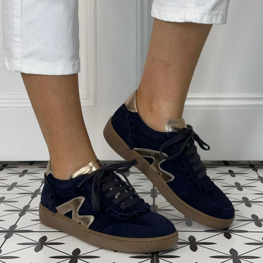 Marco Moreo Navy blue sneakers with gold accents worn indoors on a patterned floor.