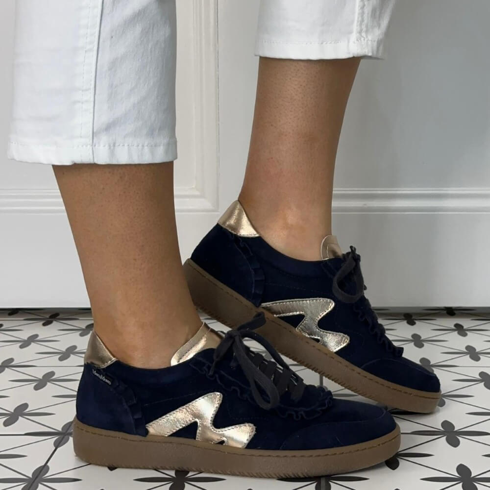Marco Moreo Navy blue sneakers with gold accents worn indoors on a patterned floor.