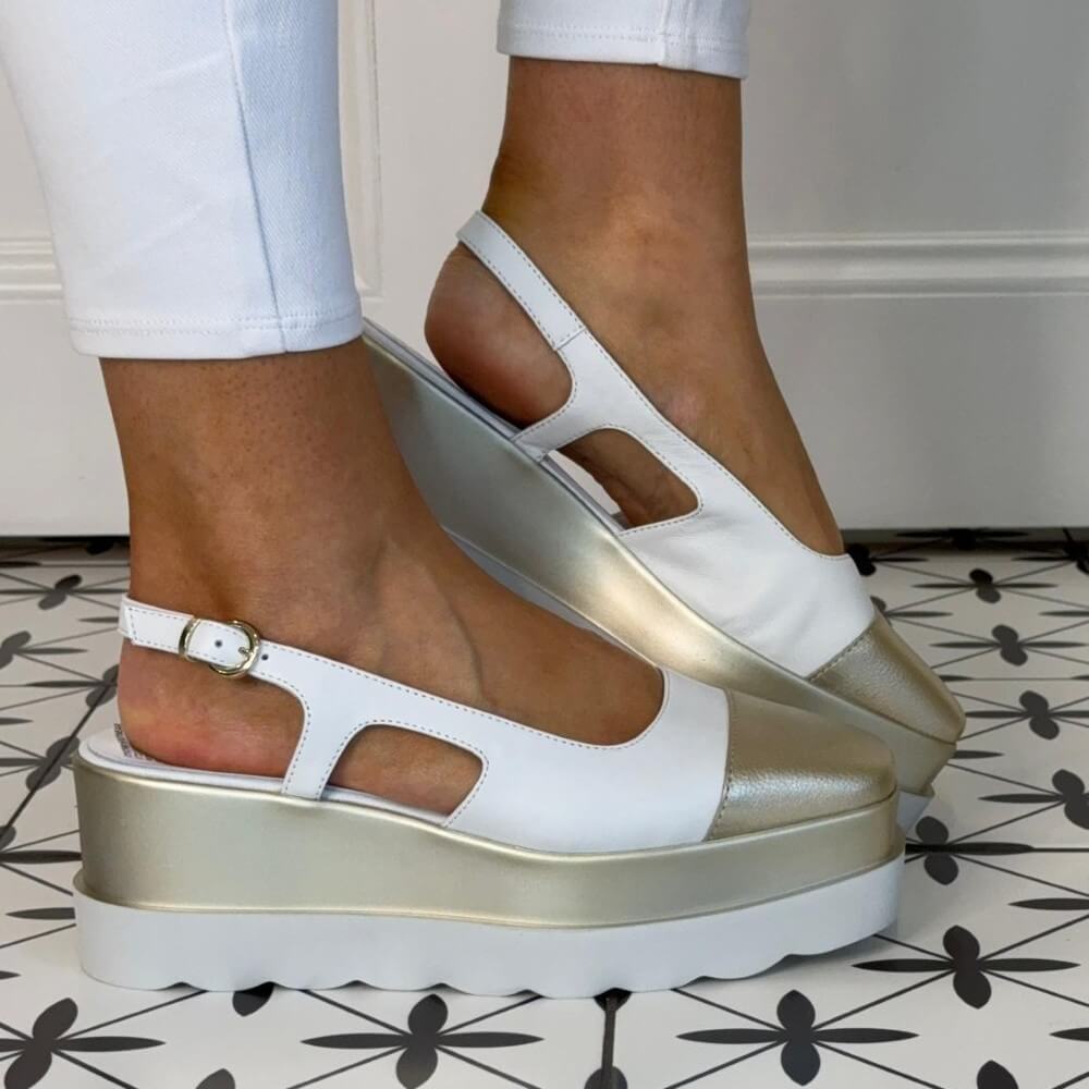 Marco Moreo White and gold platform sandals worn on a patterned floor.