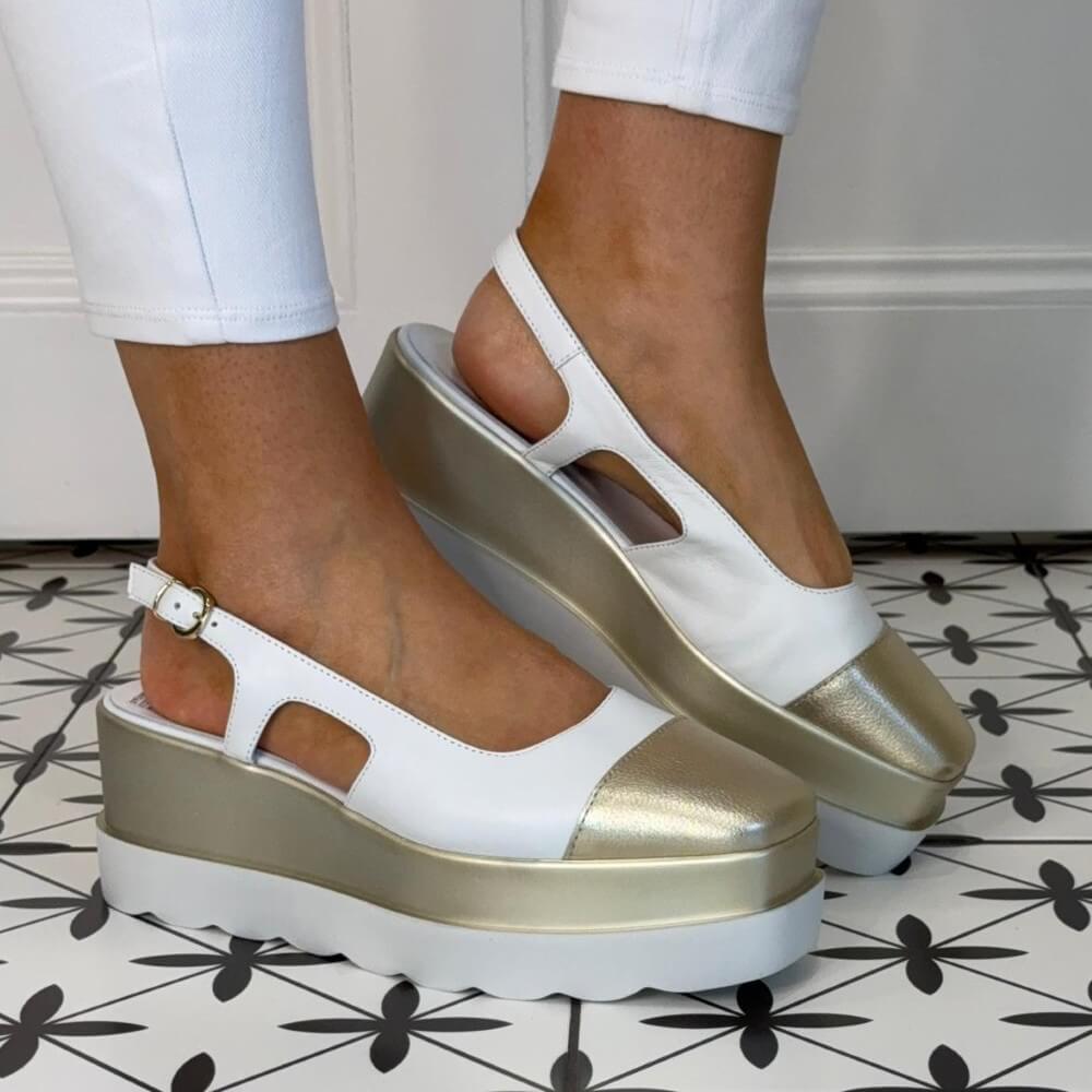 Marco Moreo White and gold platform sandals worn on a patterned floor.