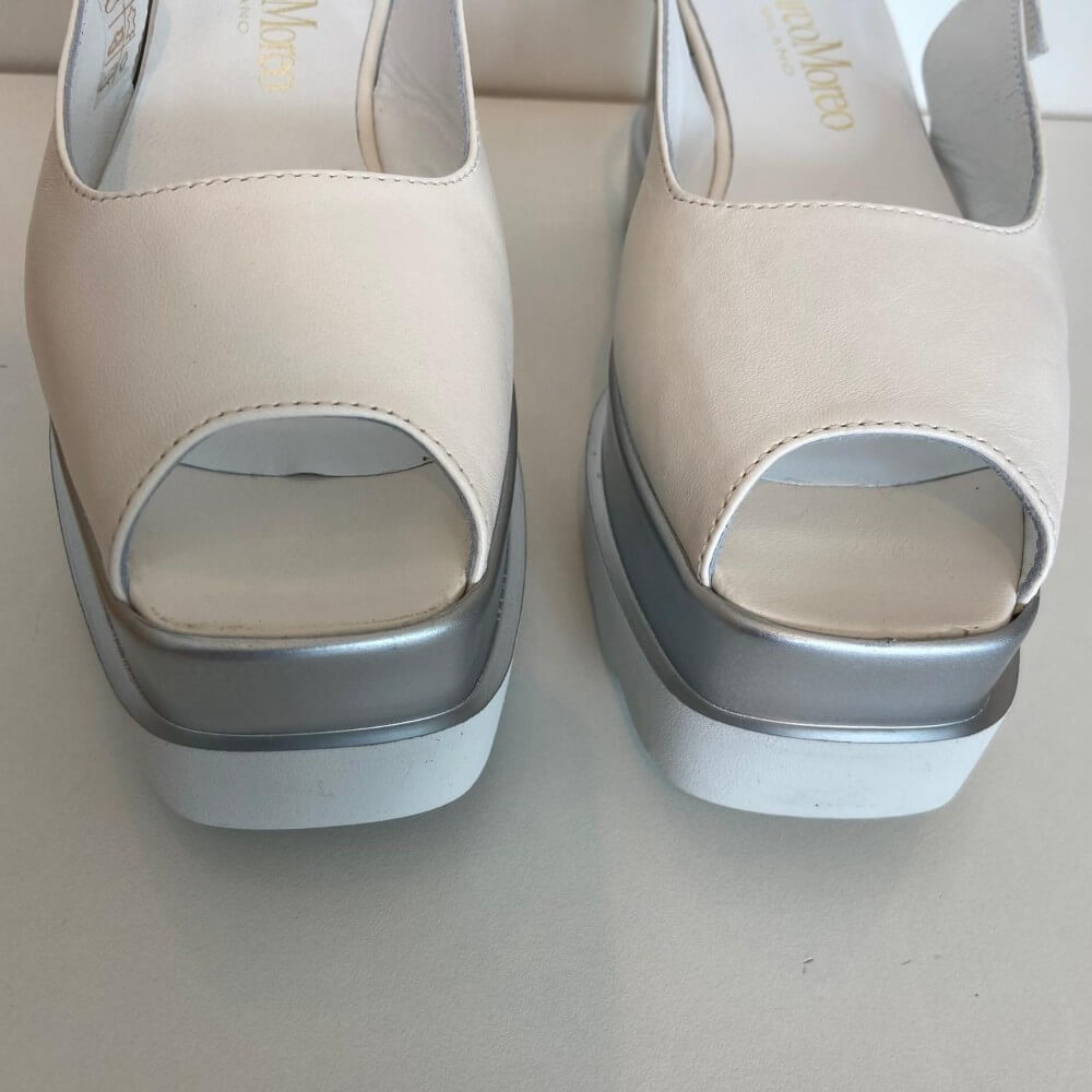 Beige open-toe shoes with silver platforms on a light background