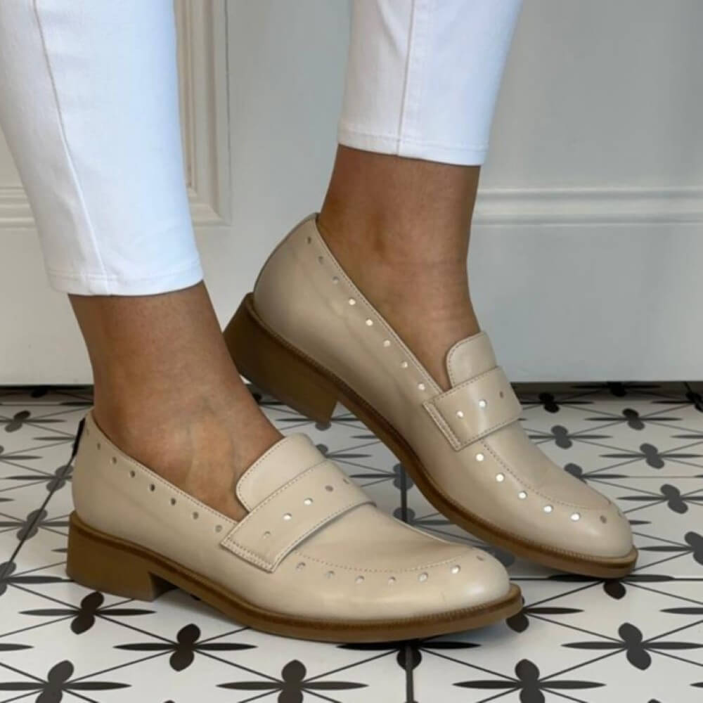Marco Moreo Beige loafers worn with white pants on a patterned floor.