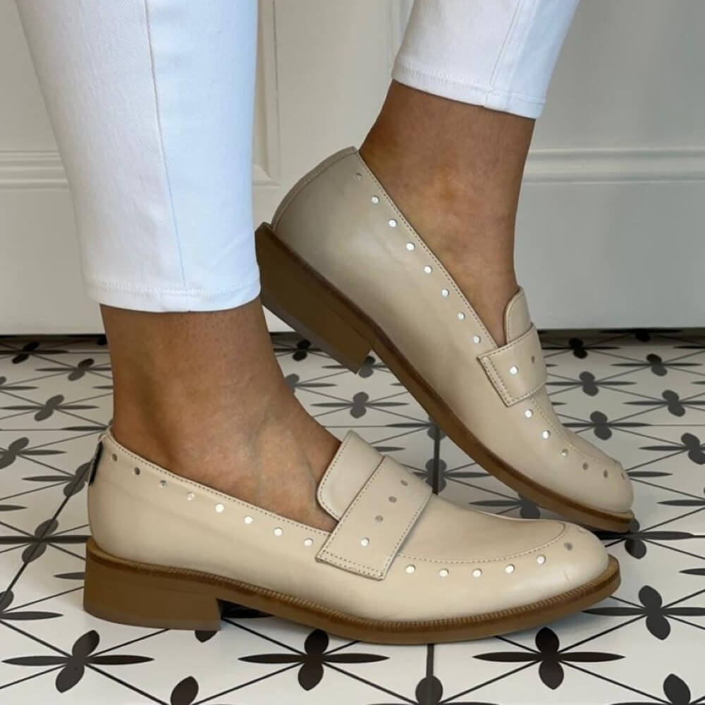 Marco Moreo Beige loafers worn with white pants on a patterned floor.