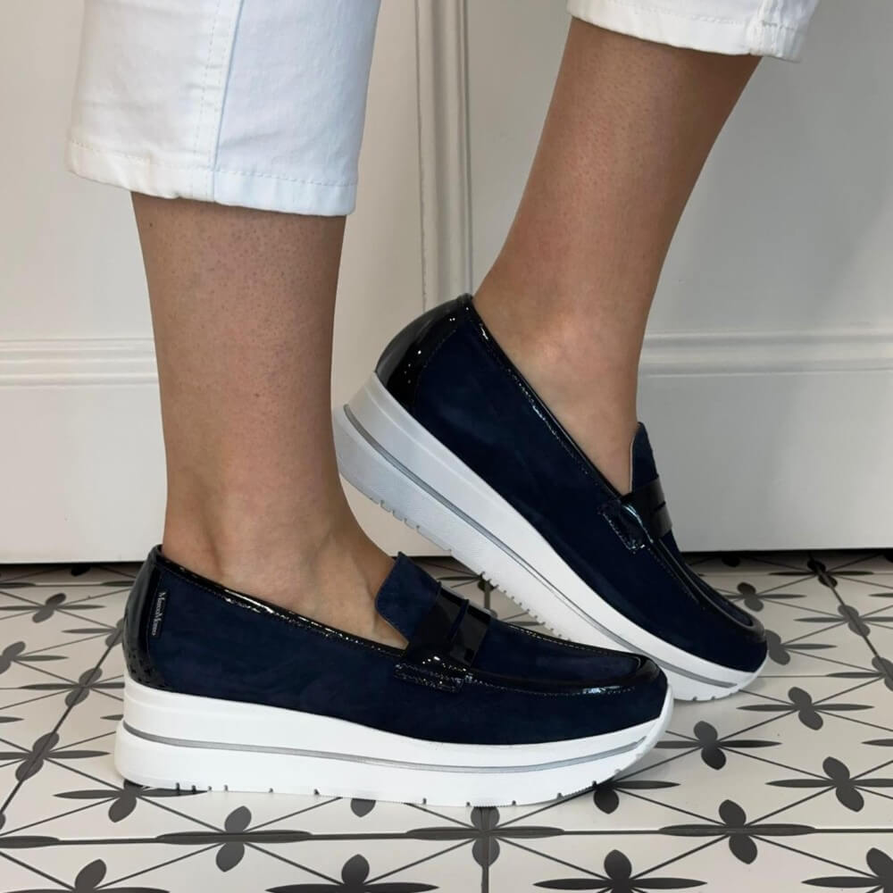 Marco Moreo Navy loafers with white soles worn by a person on a patterned floor.