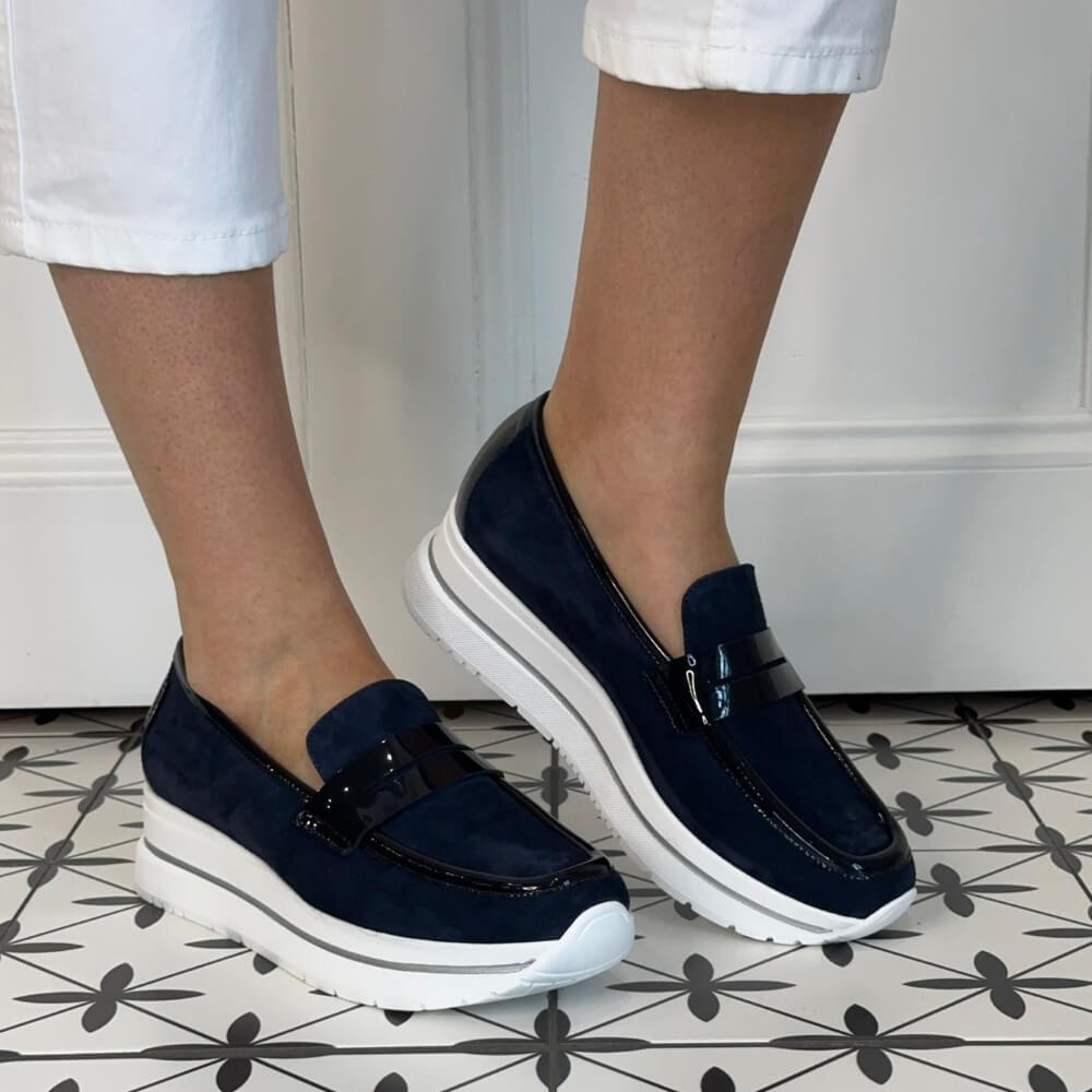 Marco Moreo Navy loafers with white soles worn by a person on a patterned floor.