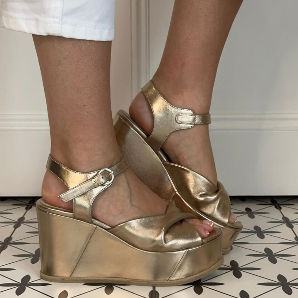Marco Moreo Gold platform sandals worn on a patterned floor.