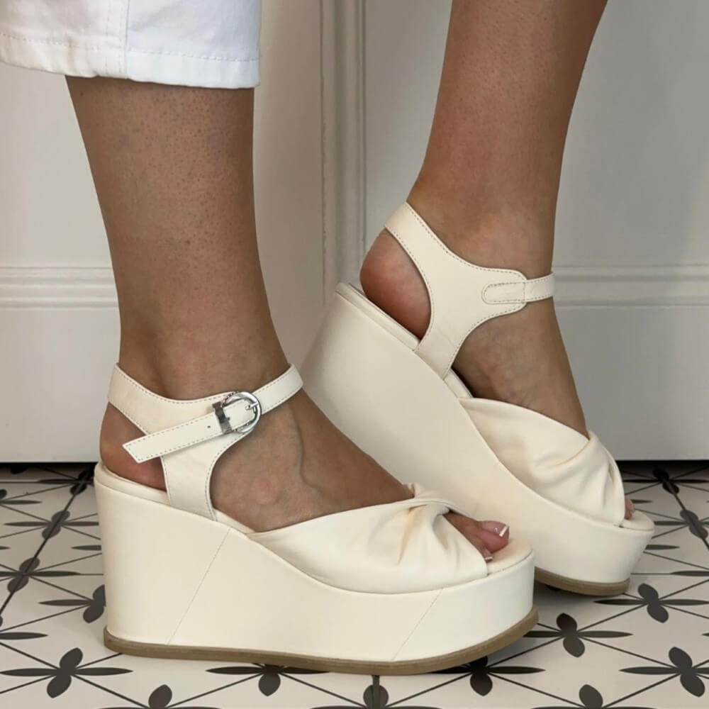 Marco Moreo White wedge sandals worn by a person on a patterned floor.