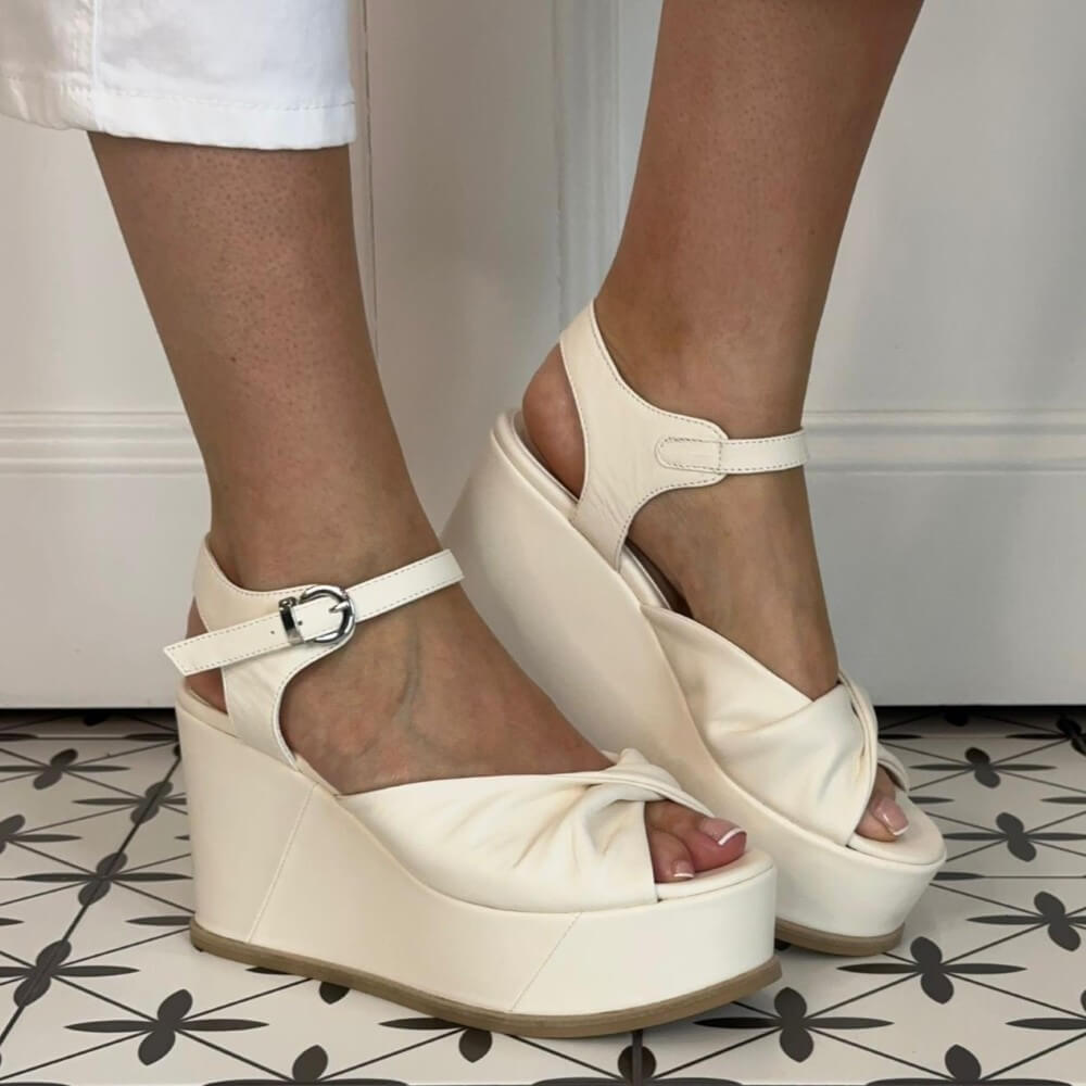 Marco Moreo White wedge sandals worn by a person on a patterned floor.