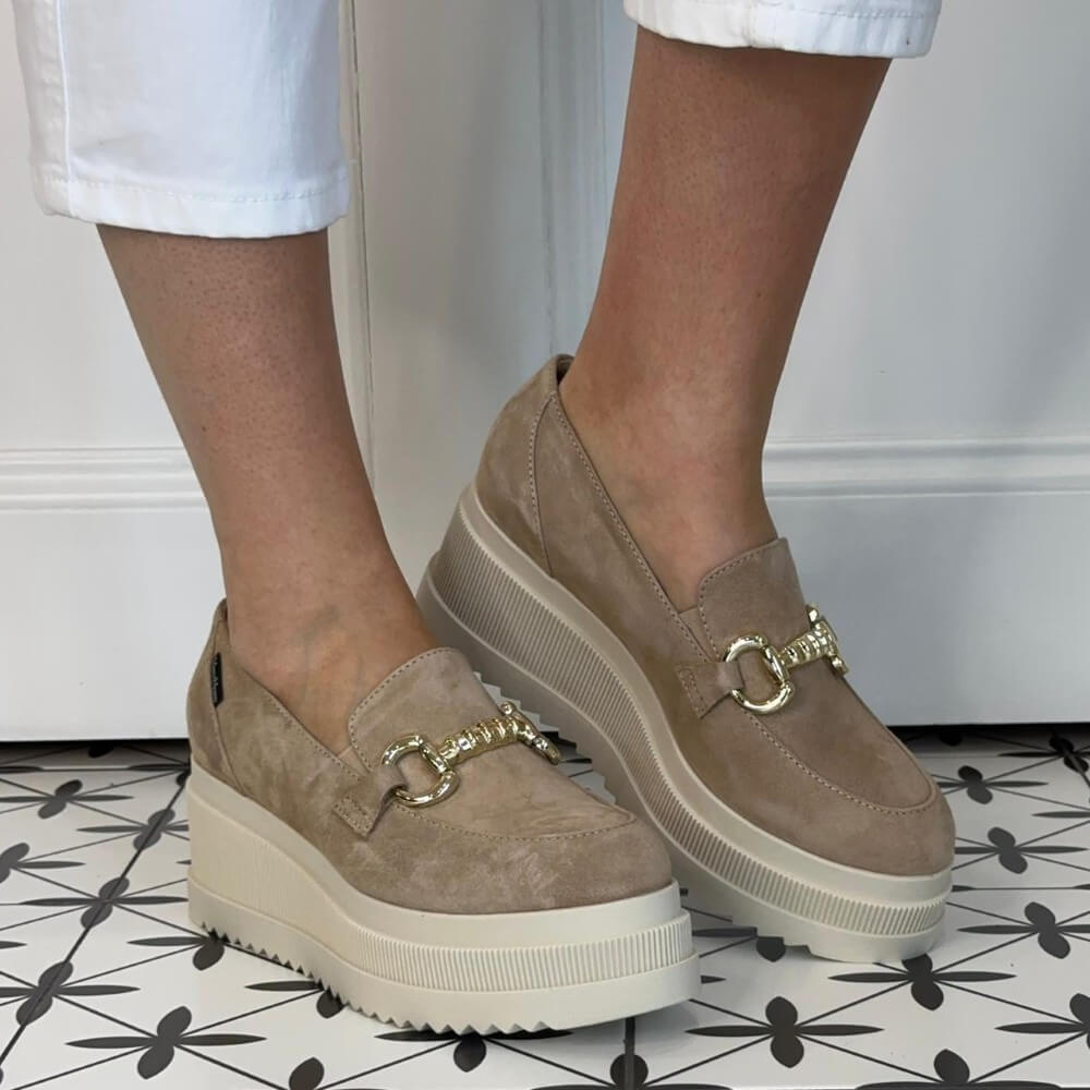 Marco Moreo Beige loafers with gold buckles worn by a person on a patterned floor.