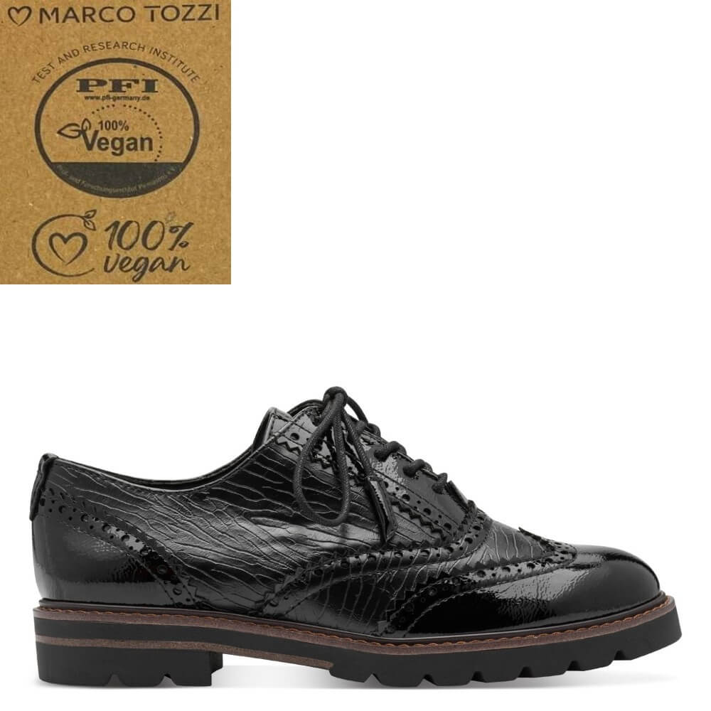 A black vegan leather oxford-style shoe with a glossy embossed texture, shown in a side profile on a white background. In the top-left corner, a kraft paper badge displays the Marco Tozzi brand and a PFI 100% Vegan certification logo.