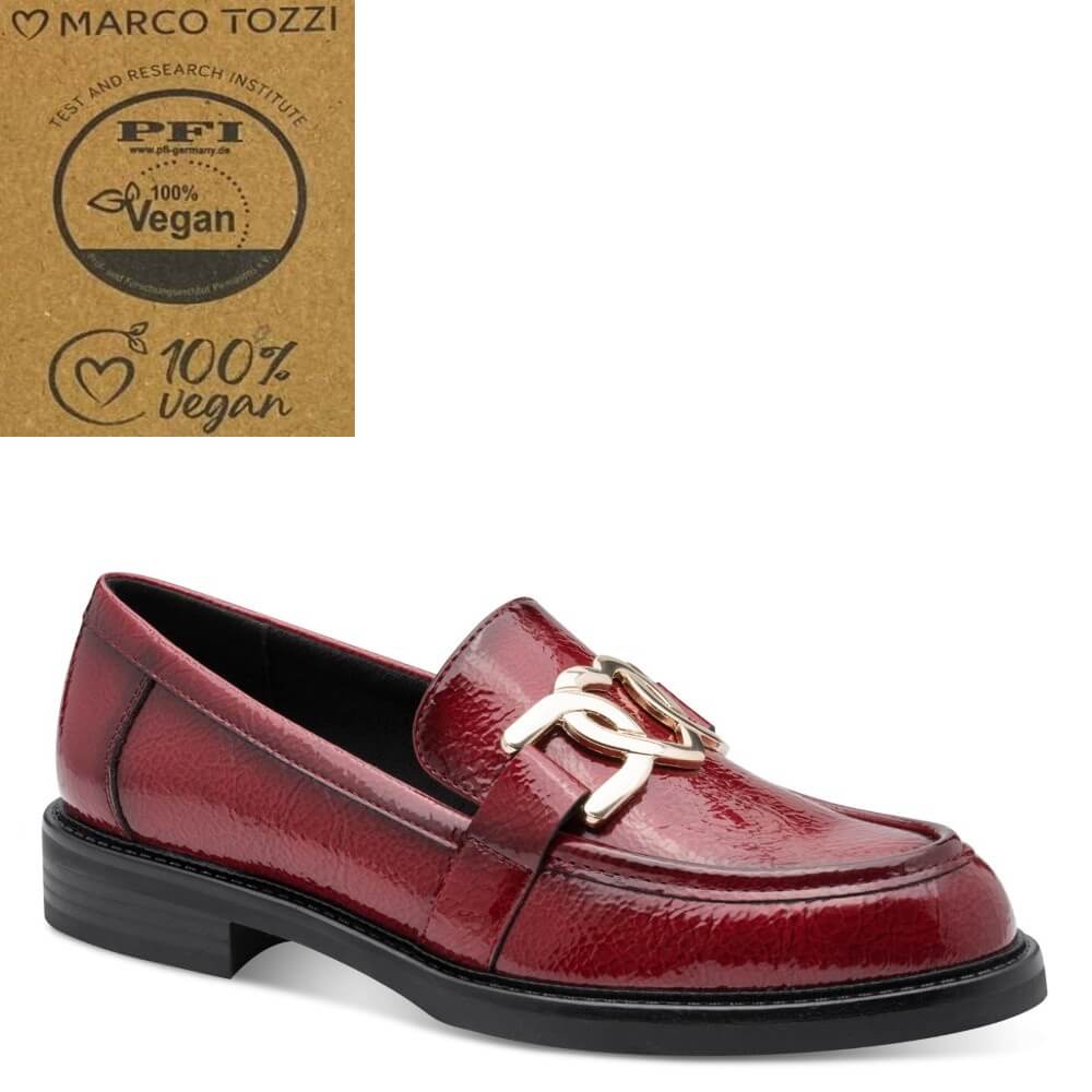 A red patent loafer by Marco Tozzi, featuring a gold-tone metal horsebit detail on the strap and a black sole, shown against a white background with a PFI 100% Vegan certification badge in the top left corner.