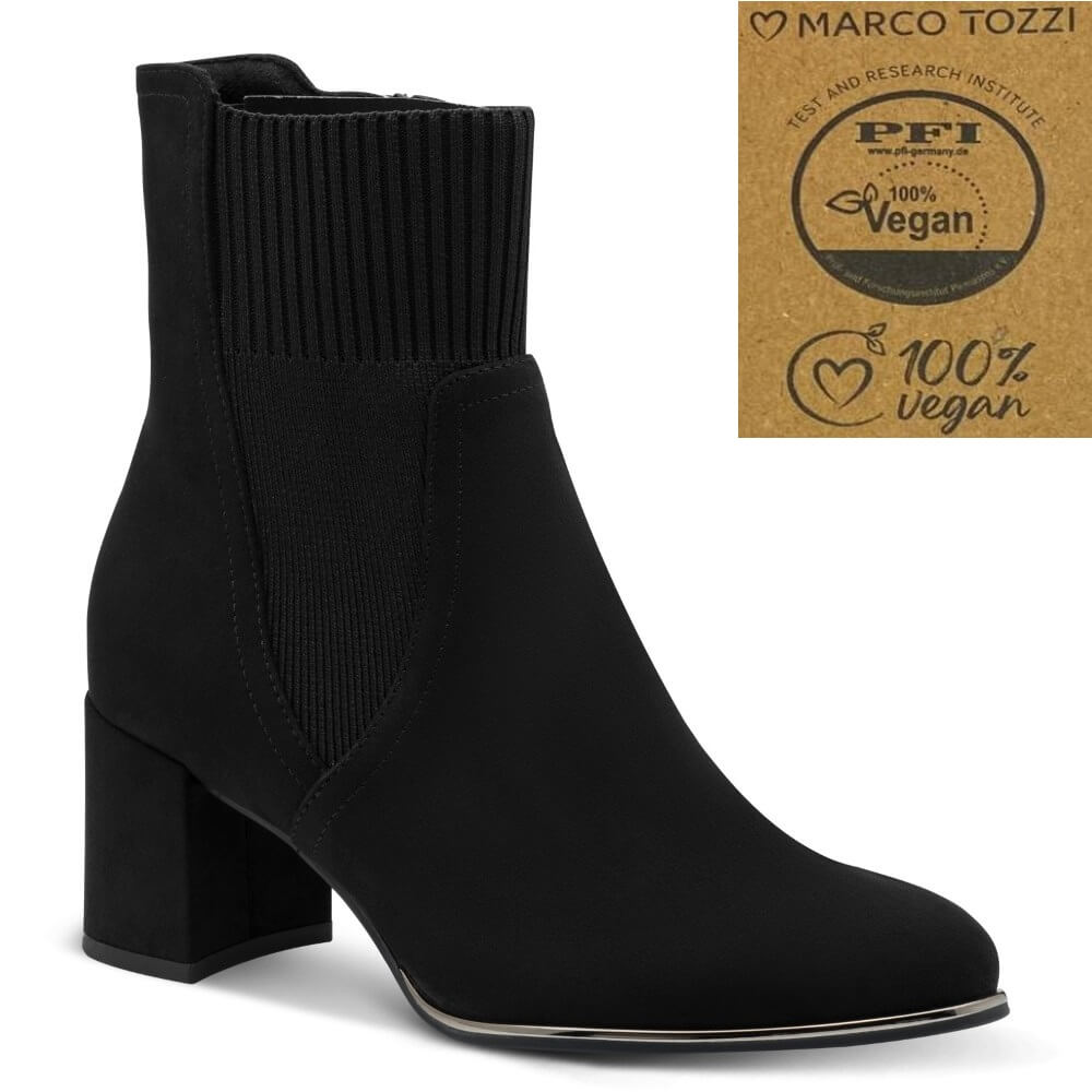 A black ankle boot with a ribbed elastic side panel and a chunky block heel, shown on a white background with a brown certification badge in the top right corner reading 'Marco Tozzi' and 'PFI 100% Vegan'.