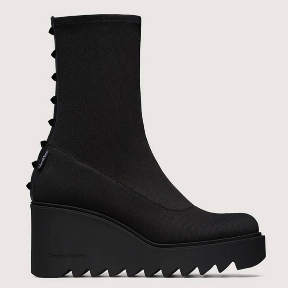 Black stretch wedge boot with studded details on a light grey background