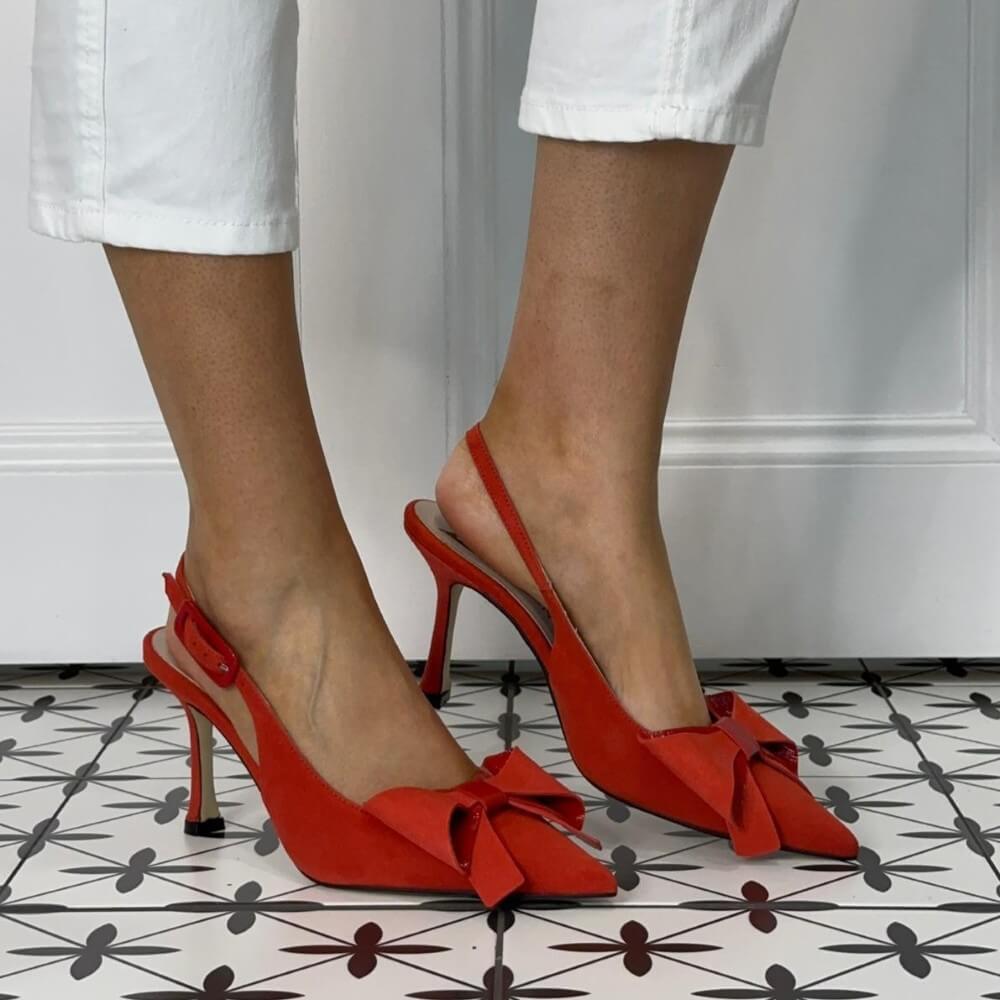 Marian Red high-heeled shoes with a bow detail worn by a person on a patterned floor.