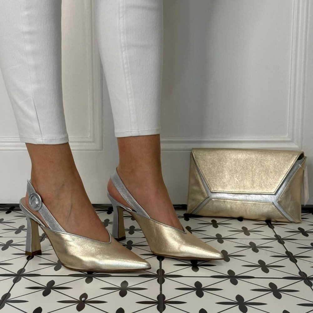 Marian Gold and Silver high-heeled shoes worn with white pants on a patterned floor. matching bag
