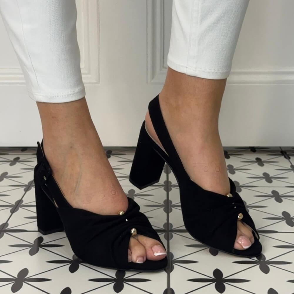 Marian Black open-toe heels worn with white pants on a patterned floor.