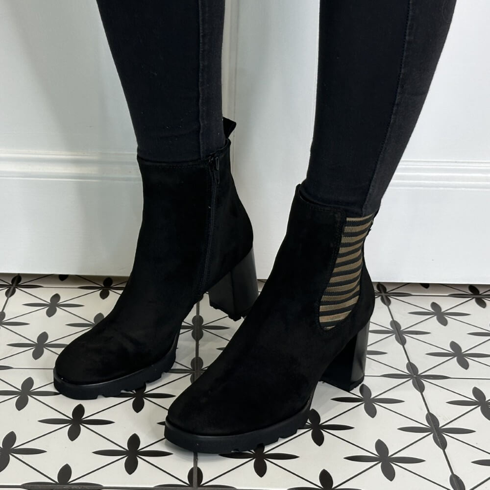 Black Platform ankle boots worn with Gold Detailing, black pants on a patterned floor.