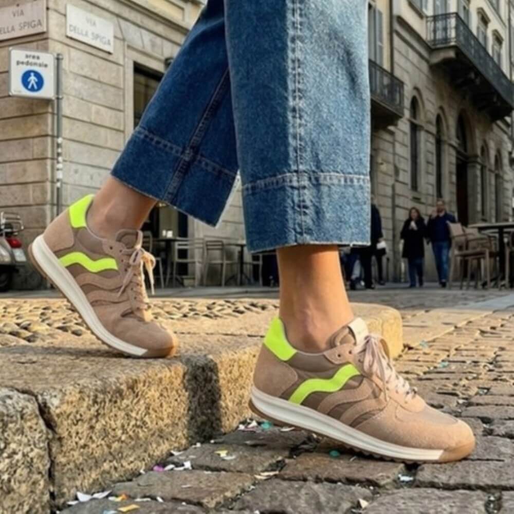 Person wearing Meline beige sneakers with Yellow green accents on a city street.