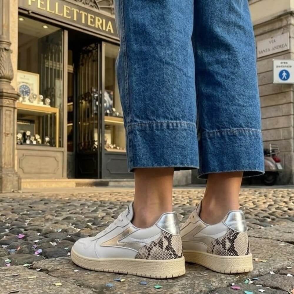 Meline White sneakers with beige soles worn by a person on stone steps in an urban setting.
