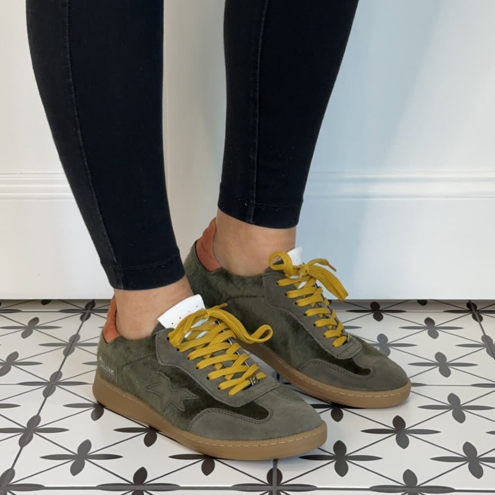 Person wearing green sneakers with yellow laces Meline Retro 526 Green