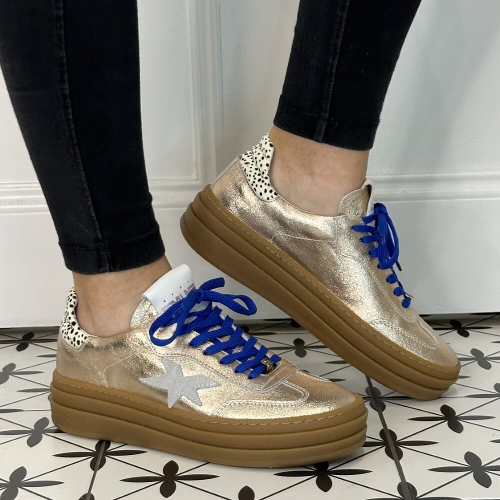 Gold sneaker with blue laces and a white star on a white background Meline Retro 525 Z-GOLD