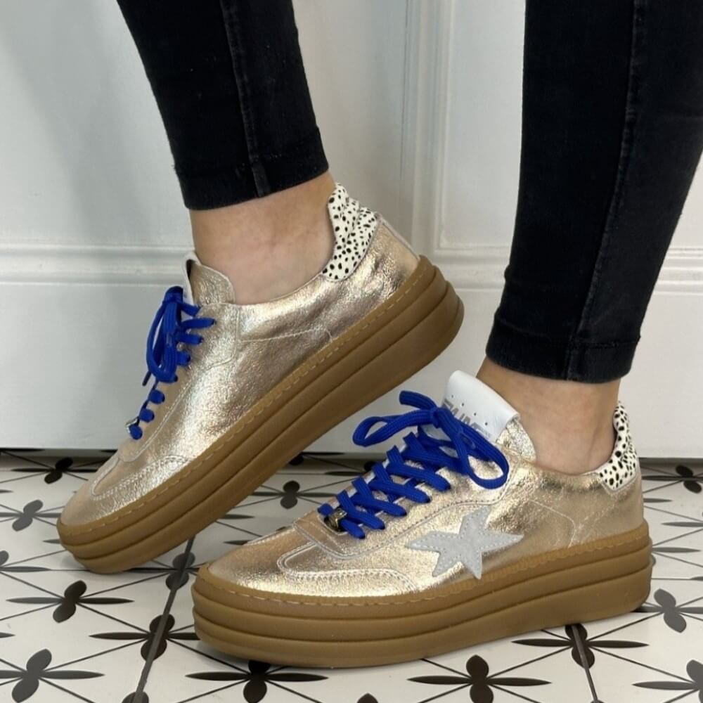 Gold sneaker with blue laces and a white star on a white background Meline Retro 525 Z-GOLD