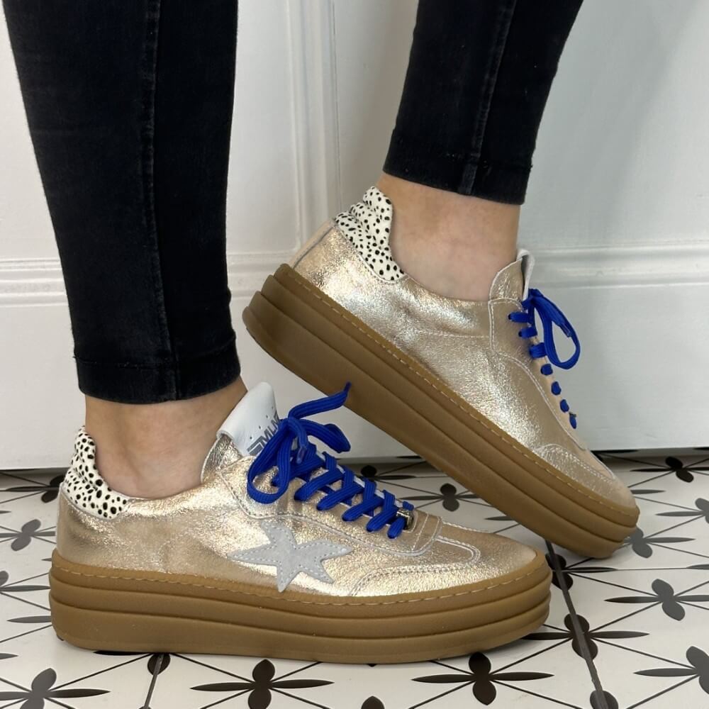 Gold sneaker with blue laces and a white star on a white background Meline Retro 525 Z-GOLD