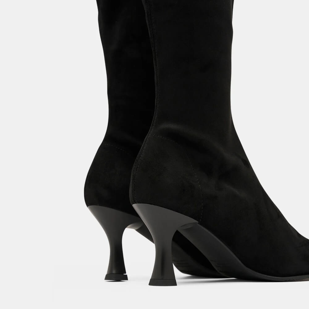 A pair of Miss Elastic black suede knee high boots with pointed toes and slim high heels, shown against a plain light grey background.