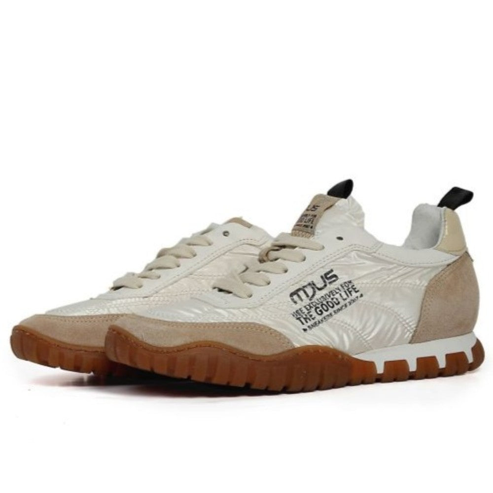 Mjus White sneakers with brown soles worn by a person on a patterned floor.