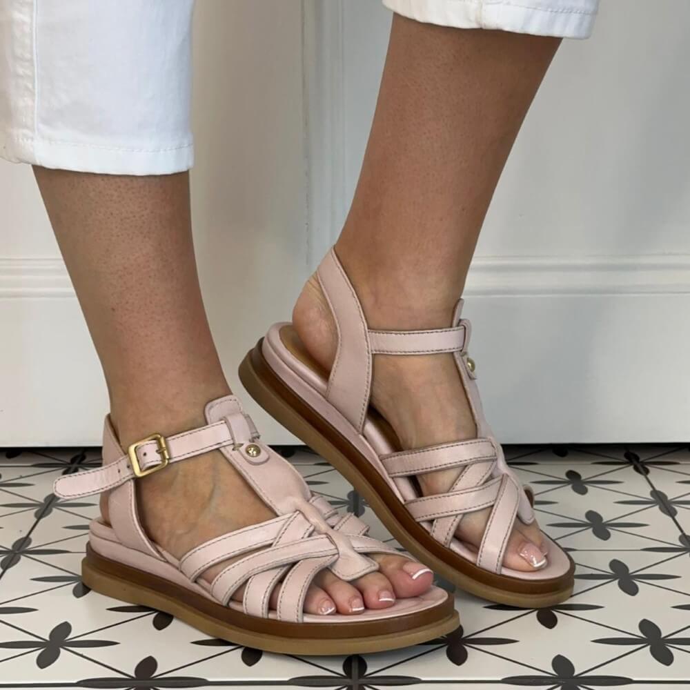 MJUS Pink sandals with brown soles worn by a person on a patterned floor.