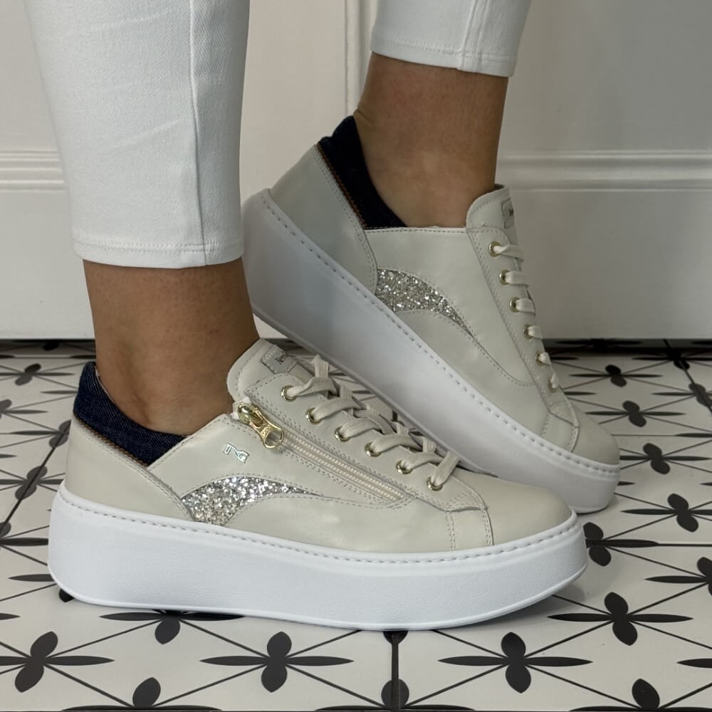 cream sneakers with glittery and denim accents worn by a person on a patterned floor. NeroGiardini E615290D