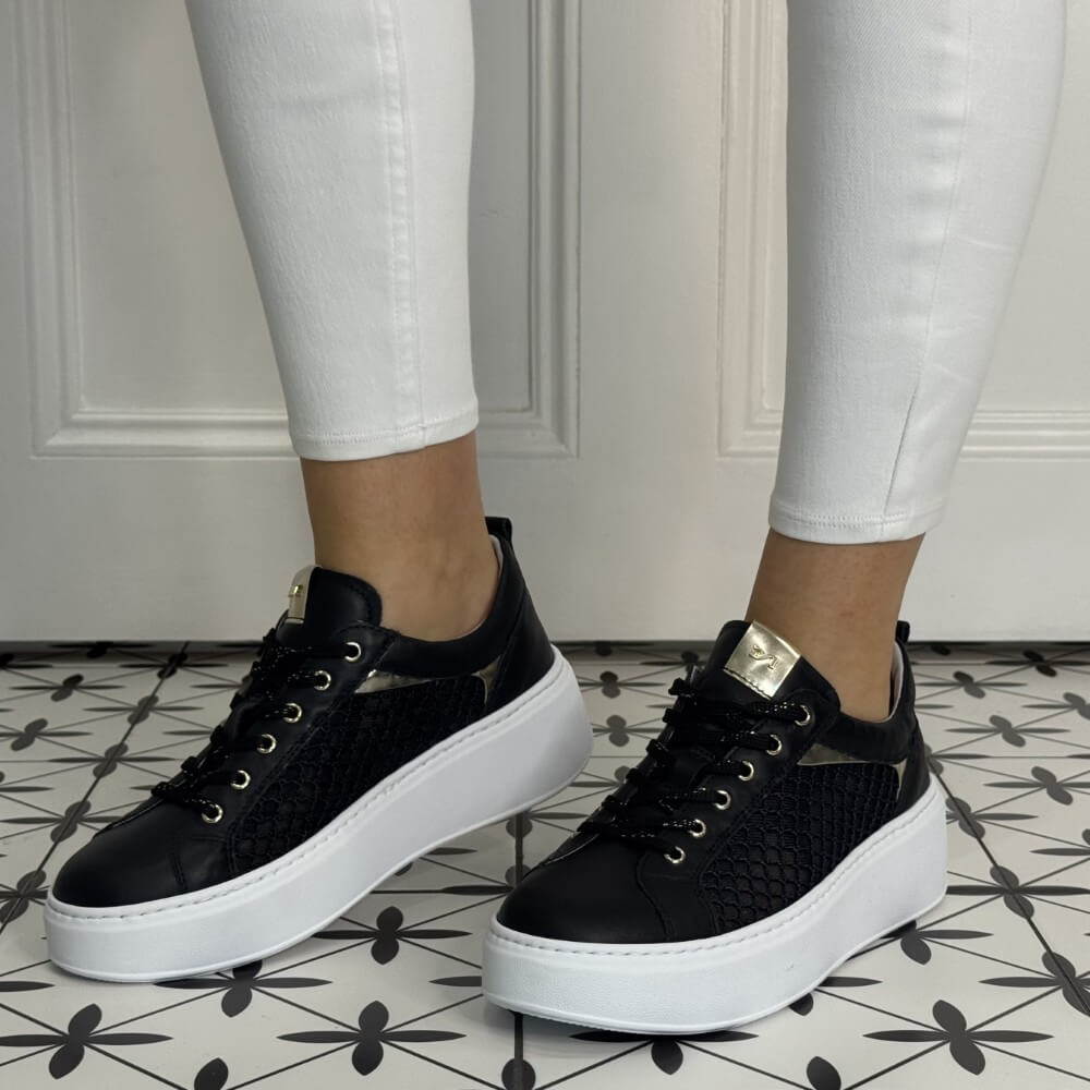 Black Mesh platform sneakers worn with white pants on a patterned floor. NeroGiardini E615292D