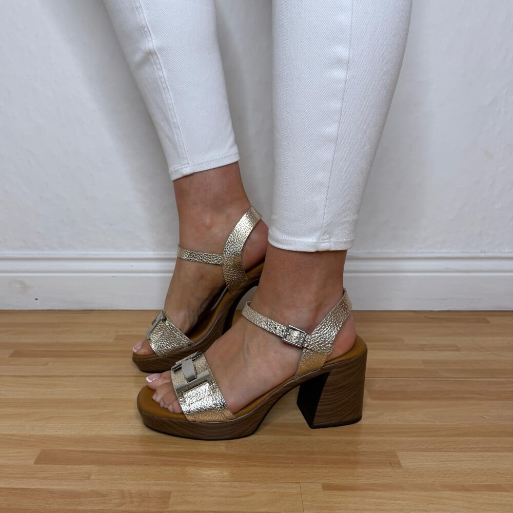 Oh My Sandals 5931 Gold metallic sandals with wooden block heels worn with white pants on a wooden floor.