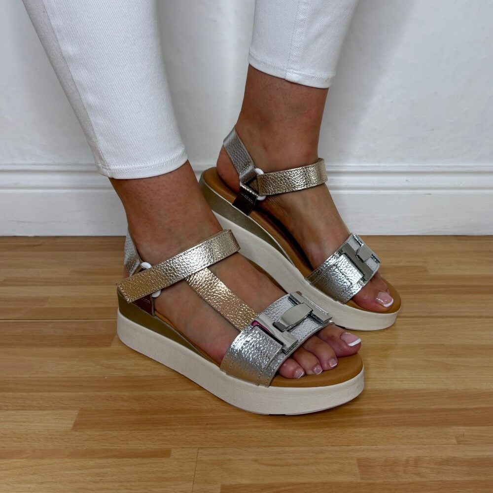 Oh My Sandals 5961 Gold and silver platform sandals worn with white pants on a wooden floor.