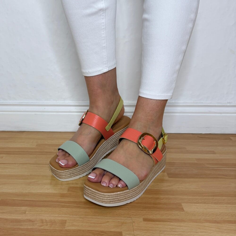 Oh MY Sandals Colourful platform sandals worn with white pants on a wooden floor.