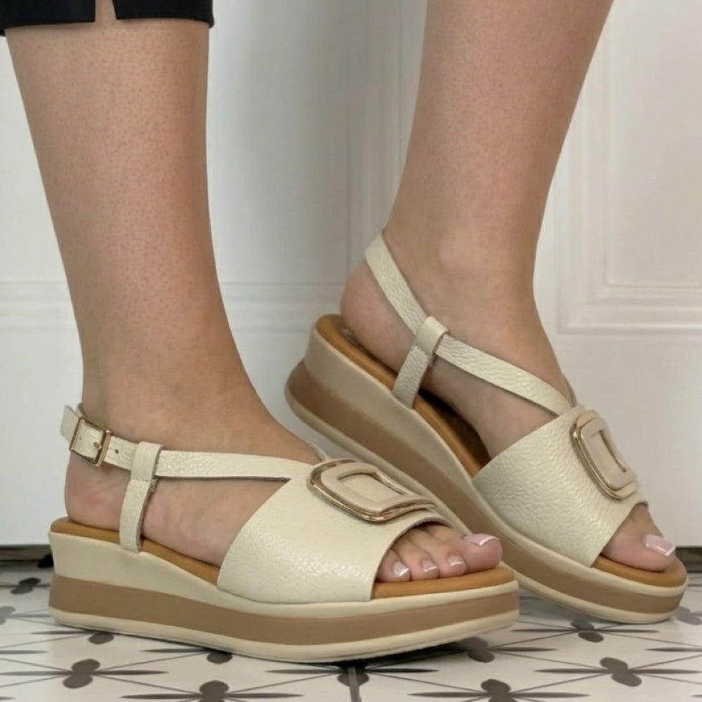 Oh My Sandals Beige sandals with brown soles worn by a person on a tiled floor.