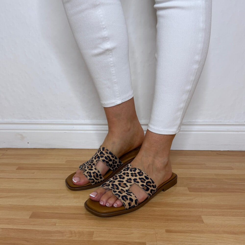 Oh My Sandals 5580 Leopard print sandals worn with white pants on a wooden floor.