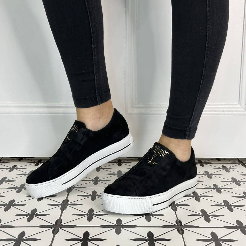 Person wearing elastic Black Leather Trainers with a white sole