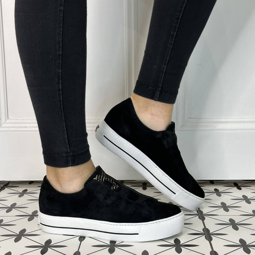 Person wearing elastic Black Leather Trainers with a white sole