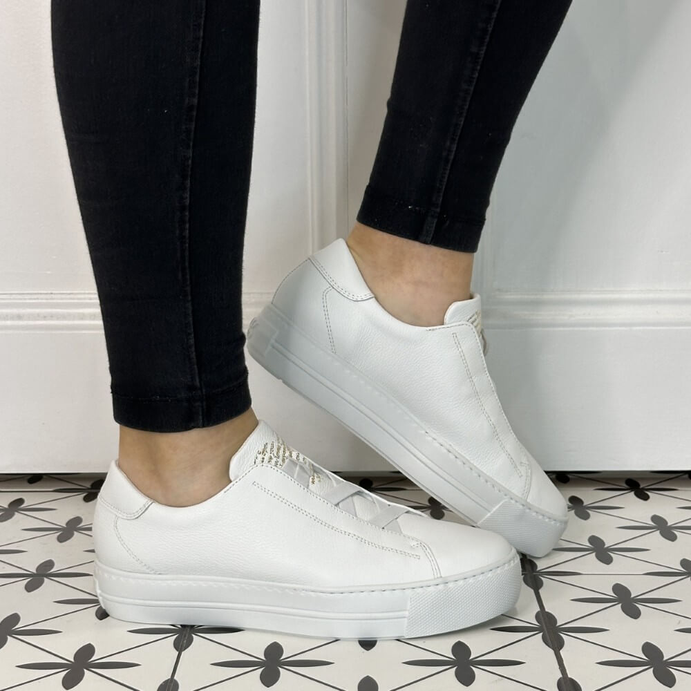 Person wearing white leather slip-on trainers