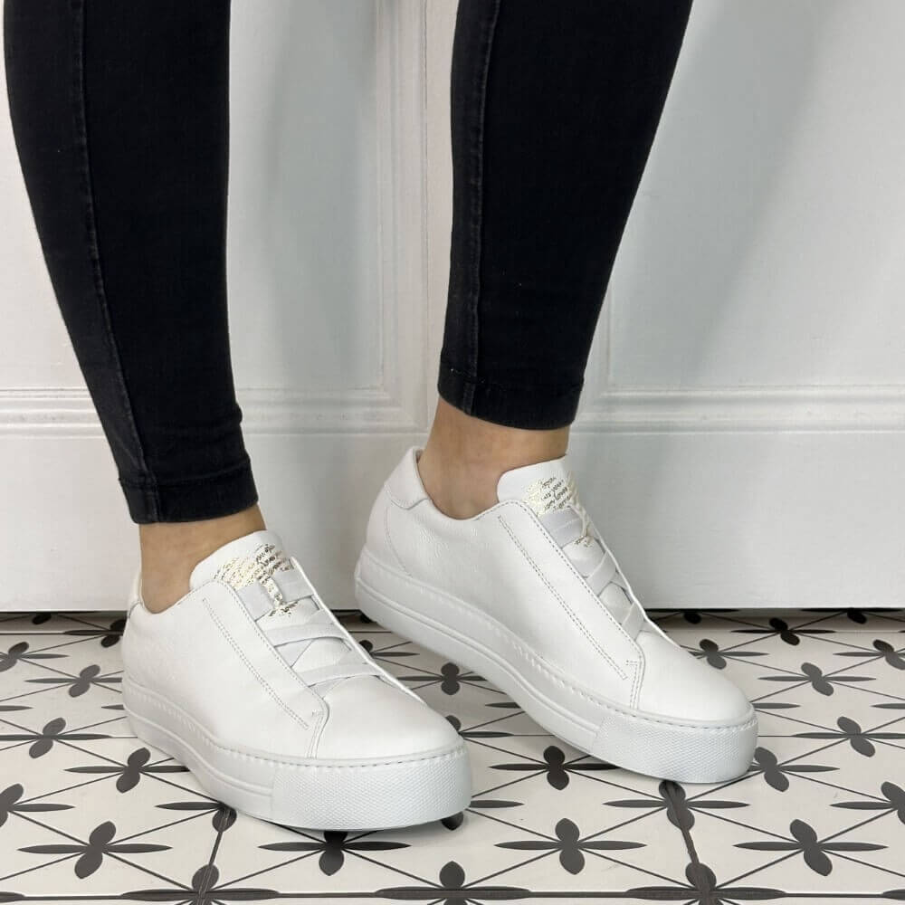 Person wearing white leather slip-on trainers