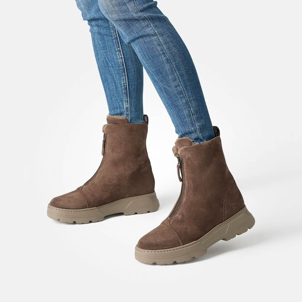 Brown suede ankle boots worn with blue jeans on a white background
