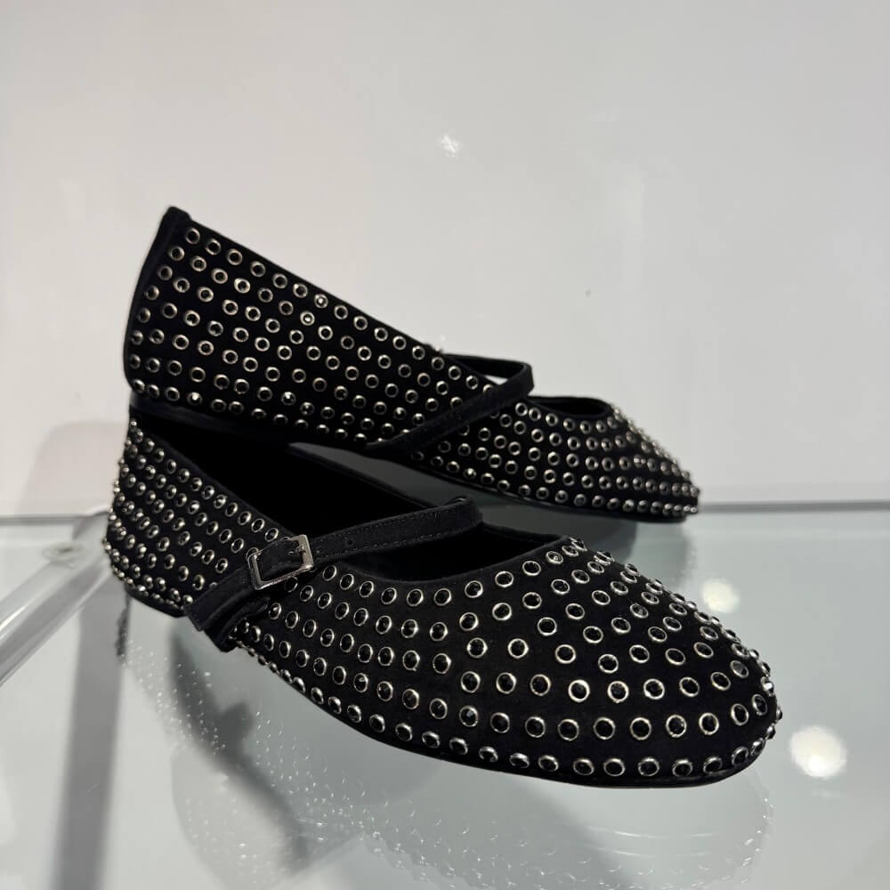 A pair of Pedro Anton Black flat shoes decorated with silver-tone metal studs and a matching black strap with a silver buckle, shown against a plain white background.